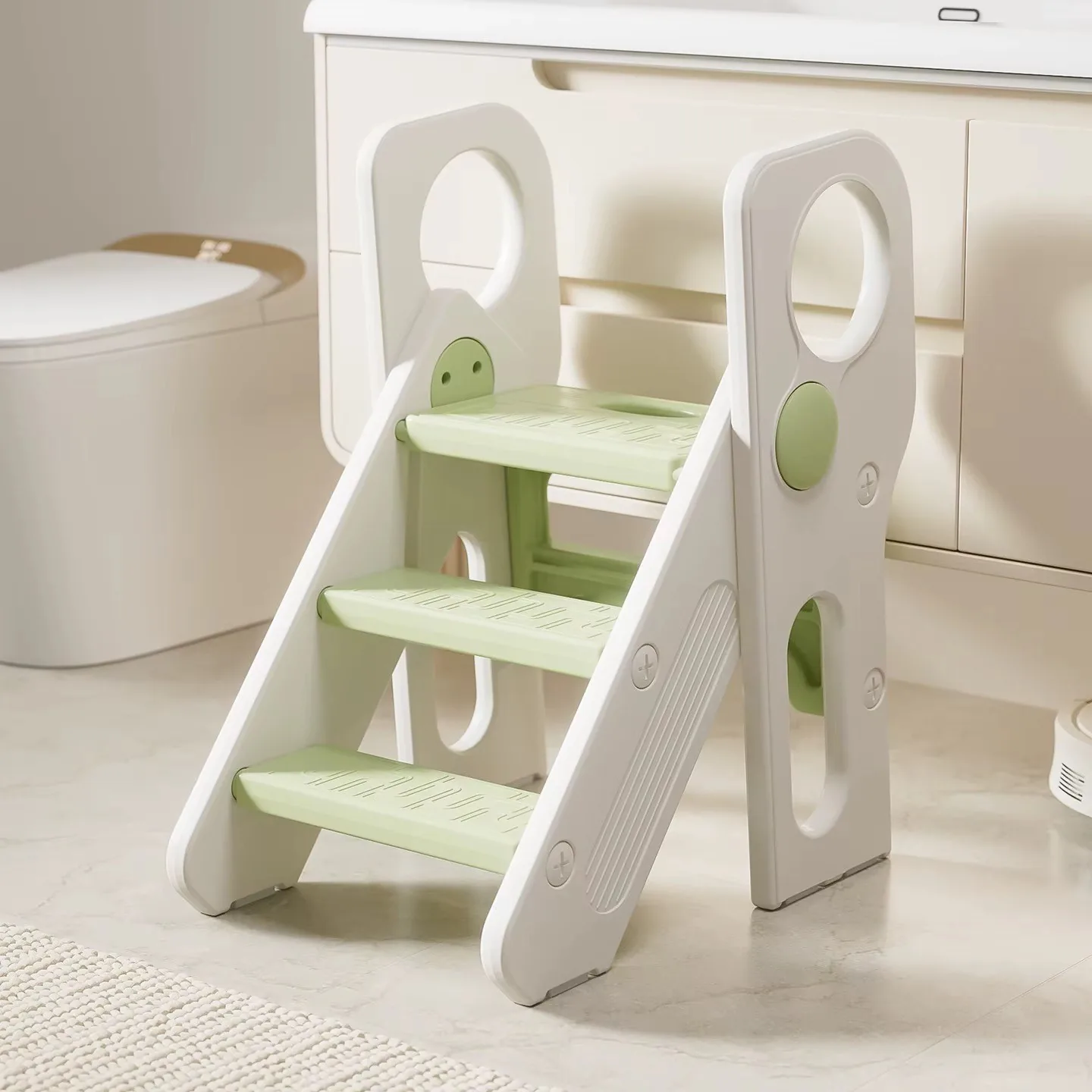 Banquito escalera de tres peldaños verde claro con laterales blancos, frente al mueble del baño