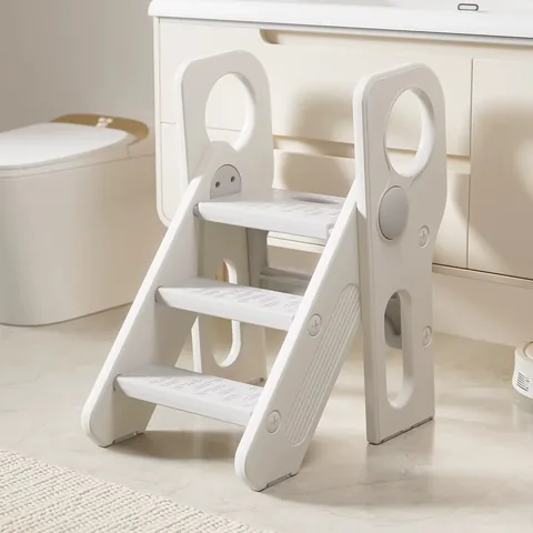 Banquito escalera de tres peldaños gris claro con laterales blancos, frente al mueble del baño