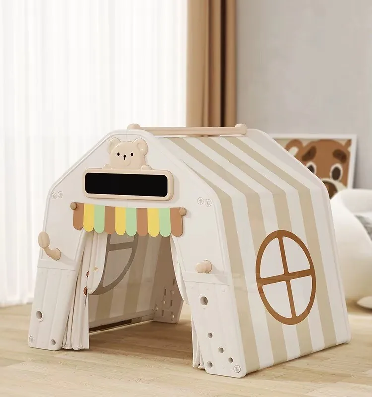Casita de juego blanca con techo de rayas beige, ventana redonda, cabecita de oso y toldito de colores
