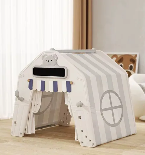 Casita de juego blanca con techo de rayas grises, ventana redonda y toldito azul con blanco