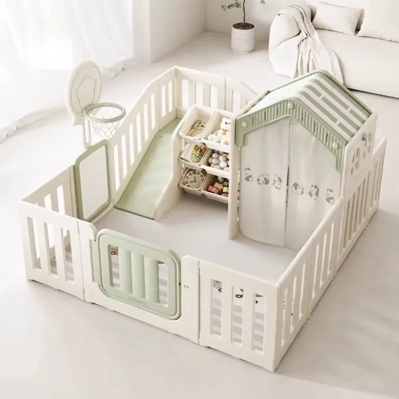 Corral blanco con tobogán verde, estante con cajas para juguetes, casita con cortinas de pandas y aro de básquet