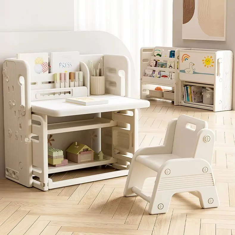 Escritorio infantil color crema con organizador para libros y lápices y silla a juego; al fondo, el mueble cerrado junto a un librero con cuentos