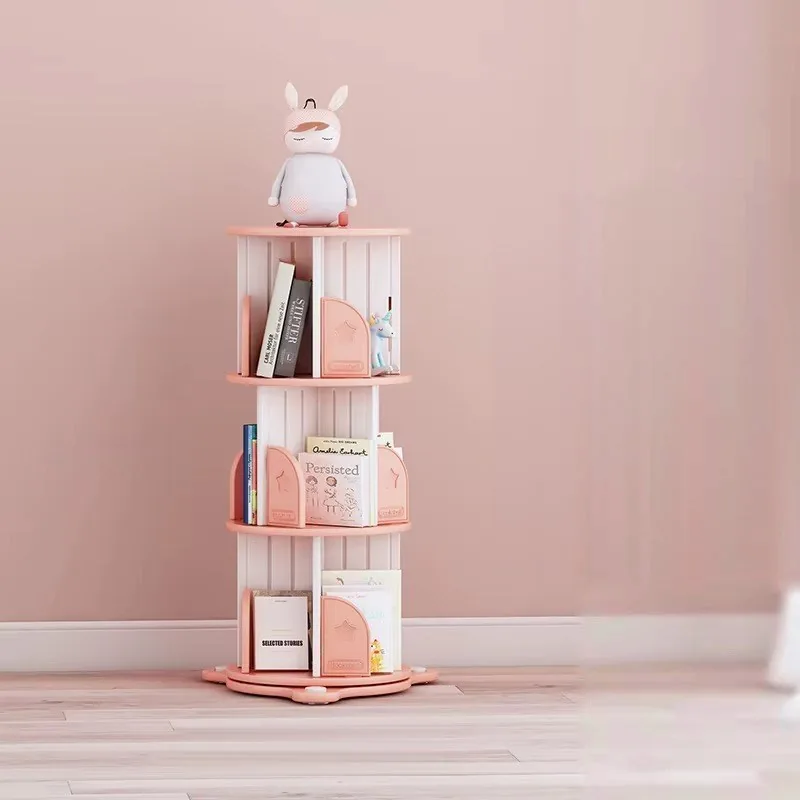 Librero giratorio rosado con blanco de tres niveles, con cuentos y una muñeca encima, junto a una pared rosada