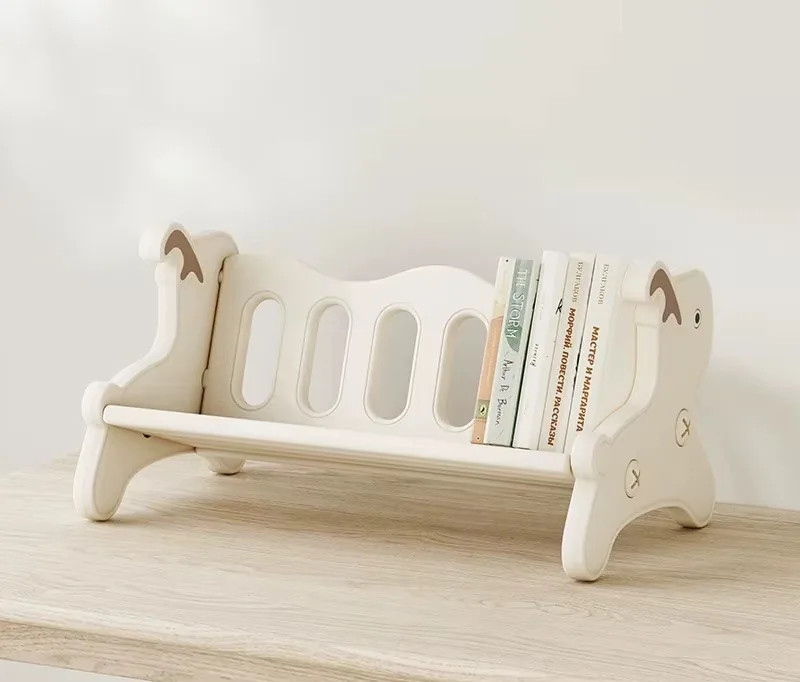 Librerito de mesa blanco crema con laterales en forma de venadito y cuentos de pie, sobre una mesa de madera