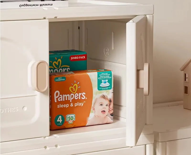 Puerta abierta del mueble blanco crema con paquetes de pañales guardados adentro
