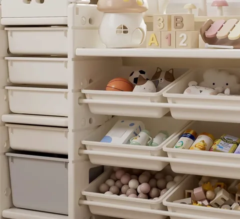 Cajas inclinadas del organizador con pelotas, peluches y juguetes guardados