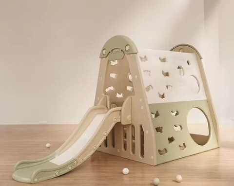 Play de pared de escalar beige y verde salvia con tobogán, sobre piso de madera con pelotas