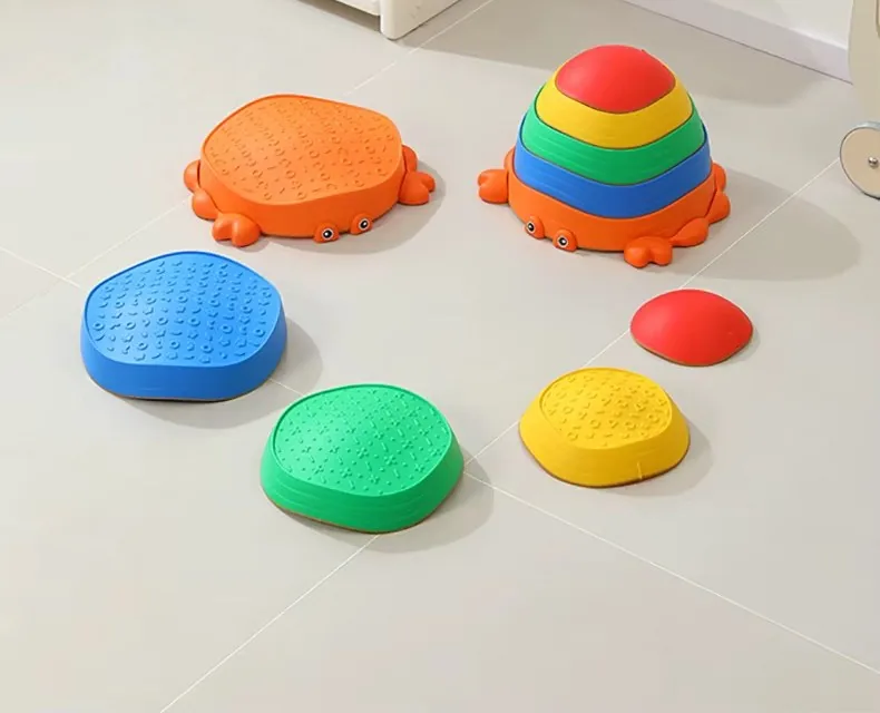 Piedras de equilibrio de colores con base de cangrejo naranja, unas sueltas en el piso y otras apiladas como una torre