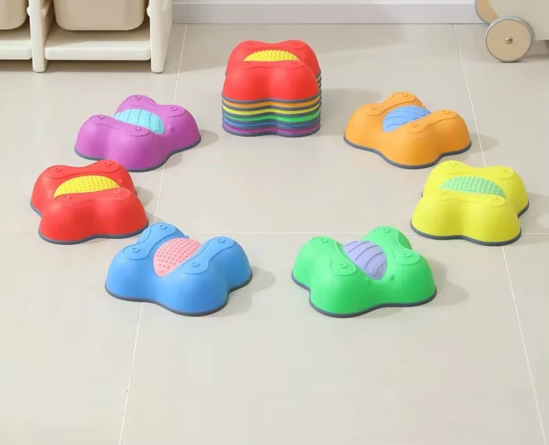 Piedras de equilibrio en forma de mariposa de seis colores acomodadas en círculo, con una pila de piezas al fondo