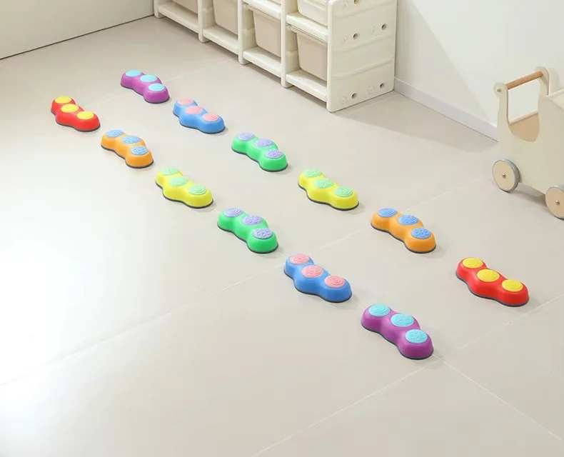Piedritas de equilibrio de seis colores acomodadas en filas sobre el piso de un cuarto infantil