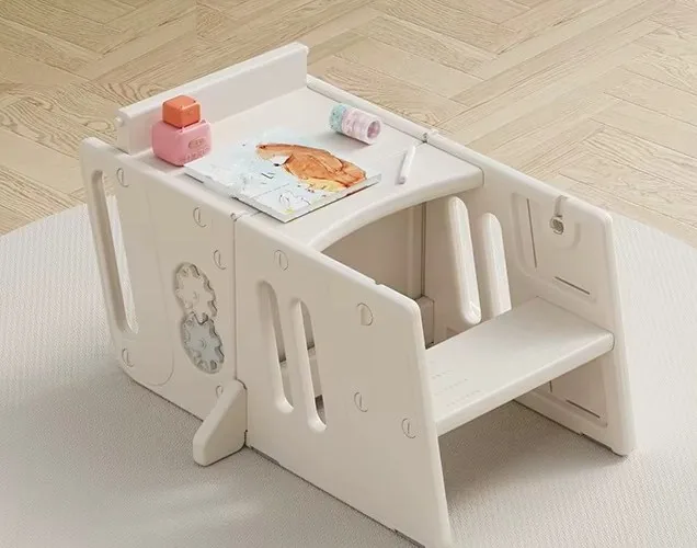 Torre de aprendizaje separada en dos piezas y armada como mesa con asiento, con un libro y juguetes encima